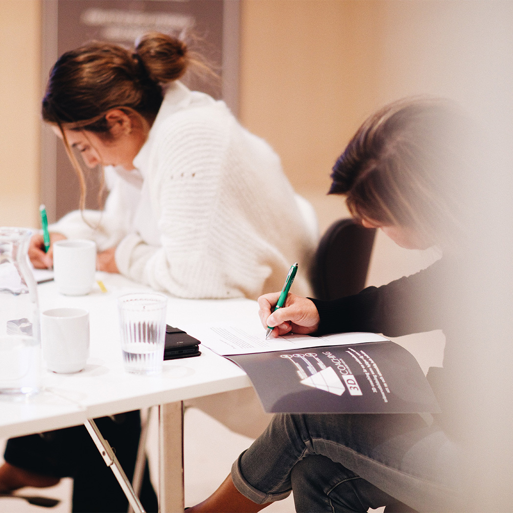 Två personer sitter och skriver i varsin anteckningsbok