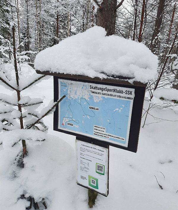 Snötäckt skylt med en karta.